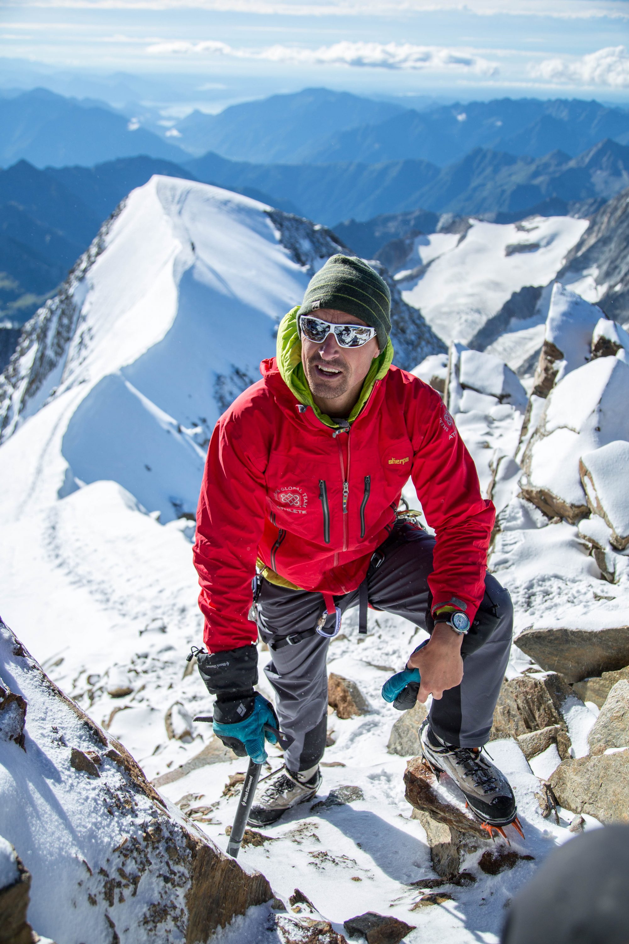 Kenton Cool in red jacket climbing up a mountain