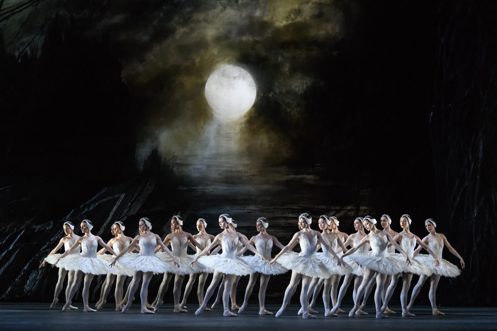Ballet dances dressed in white leotards and tu-tus under a full moon.