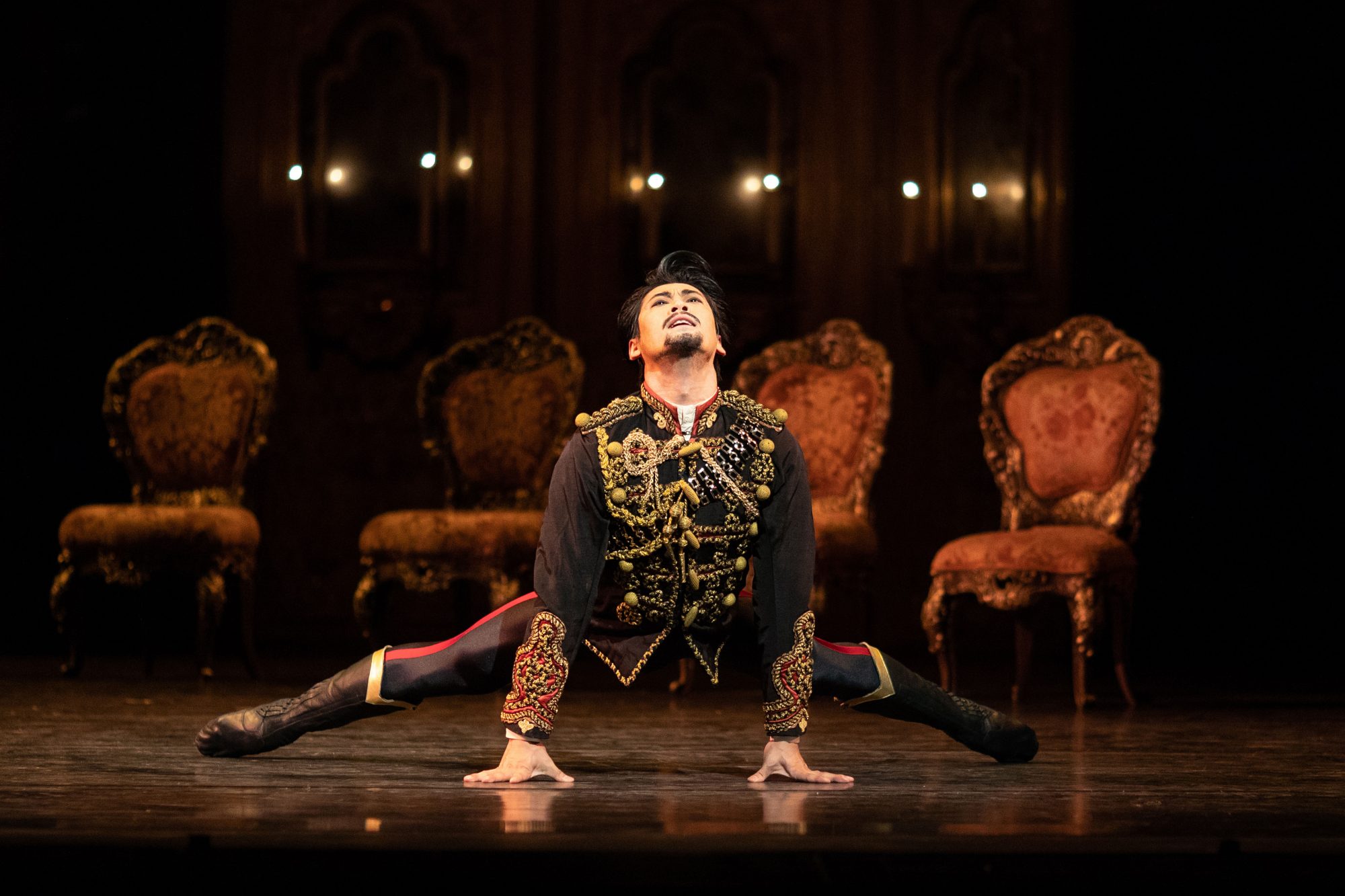 A man in a gold and black jacket bending on the floor