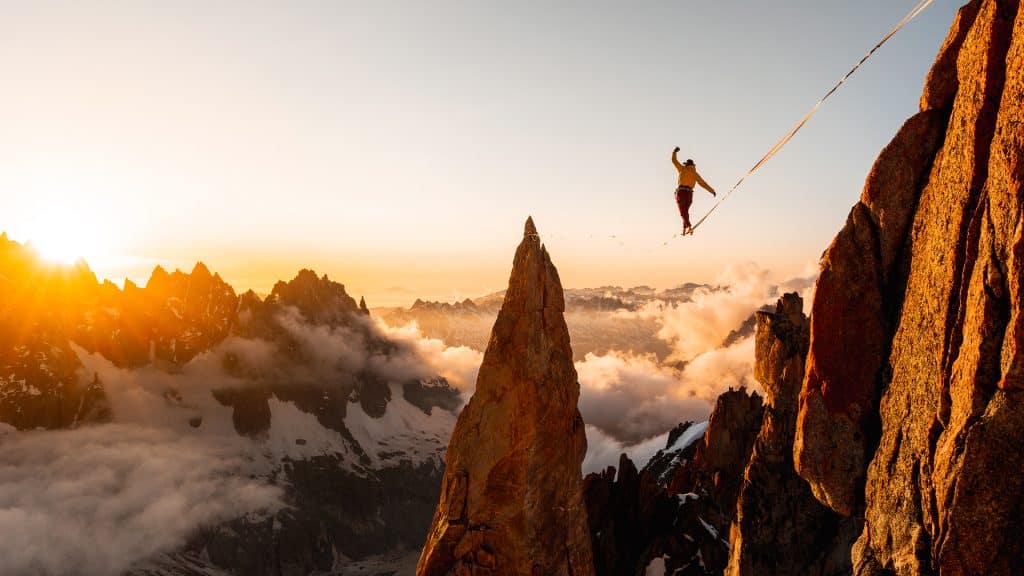 A figure walks across a tightrope, seemingly in mid-air in a mountain landscape. Picture by Antoine Mesnage
