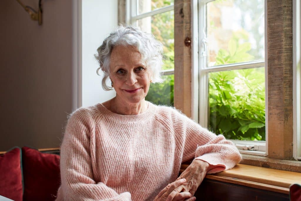 A headshot of Philippa Gregory with a window looking onto a garden